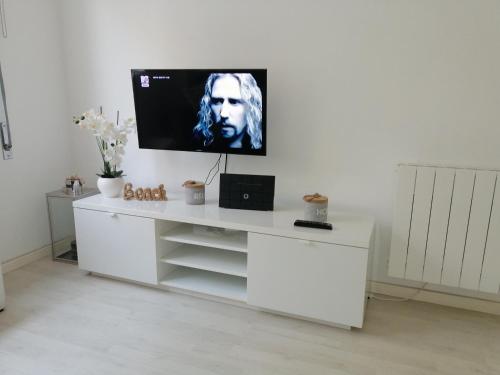 een wit entertainmentcentrum met een flatscreen-tv aan de muur bij Home Beach in Figueira da Foz