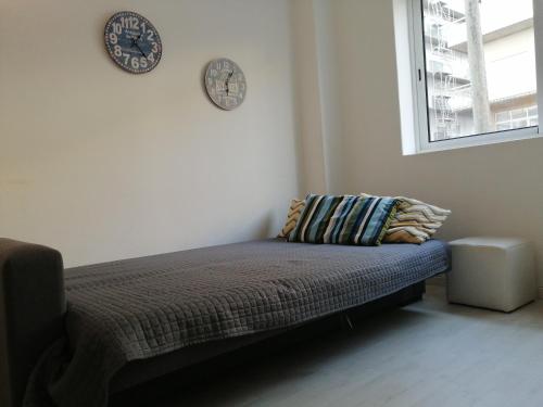 a bed in a room with two clocks on the wall at Home Beach in Figueira da Foz