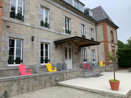 a group of colorful chairs sitting outside of a building at Gîtes grands groupes - Château des Forges Gouville in Gouville-sur-Mer