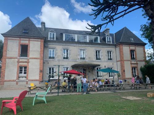 a large building with people sitting at tables in front of it at Gîtes grands groupes - Château des Forges Gouville in Gouville-sur-Mer