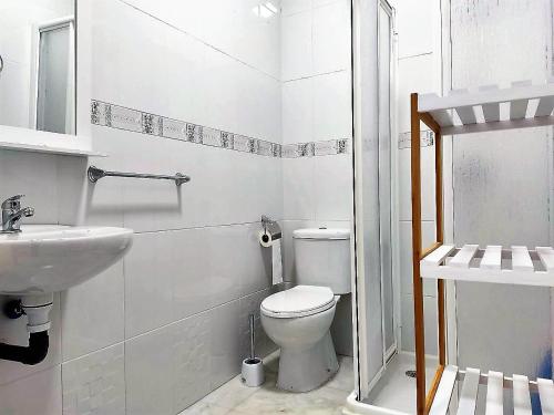 a white bathroom with a toilet and a sink at Apartamento Argentina, A/C, WIFI in Sanlúcar de Barrameda
