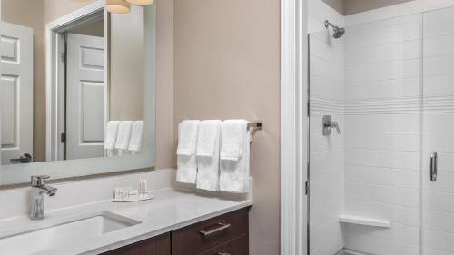 a bathroom with a sink and a mirror and a shower at TownePlace Suites by Marriott Charlotte Arrowood in Charlotte