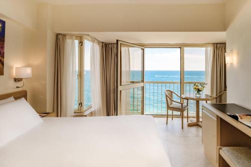 a hotel room with a bed and a view of the ocean at The Diplomat Hotel in Sliema
