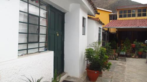 a green door on a white building with plants at Hospedaje Familiar Kitamayu Pisac in Pisac