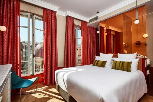 a bedroom with a large white bed and red curtains at Hotel De Cambis in Avignon