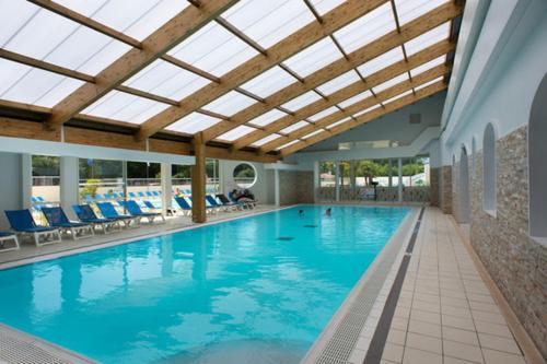 a large swimming pool with blue chairs and a ceiling at Charmant mobile-home 4 personnes - Camping 4 étoiles in Saint-Jean-de-Monts