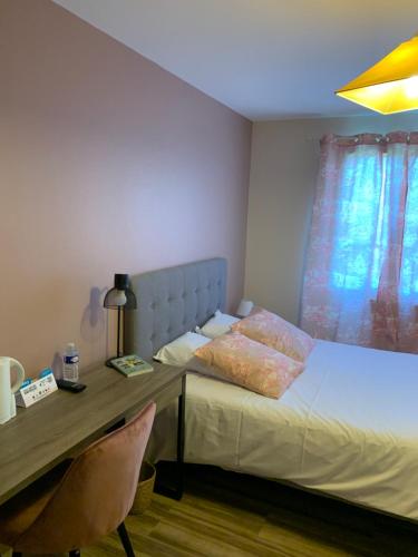 a bedroom with a bed with a desk and a bed sidx sidx sidx at LOGIS-Hôtel Restaurant Auberge Les Vallées Du Perche in Vichères