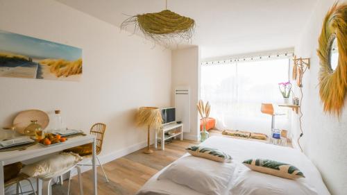 une chambre blanche avec un lit, un bureau et une fenêtre dans l'établissement Studio Le Surfing de Carnon plage, à Carnon-Plage