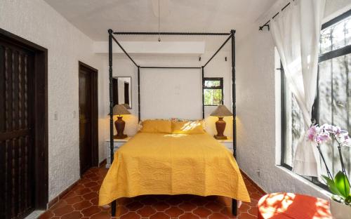 a bedroom with a bed with a yellow bedspread at Garden of Dreams Boutique Hotel in Ajijic