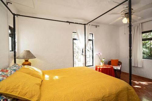 a bedroom with a bed with a yellow bedspread at Garden of Dreams Boutique Hotel in Ajijic