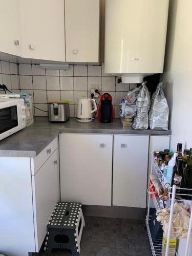une cuisine avec des armoires blanches et un micro-ondes dans l'établissement Maison campagne/mer, à Gouville-sur-Mer