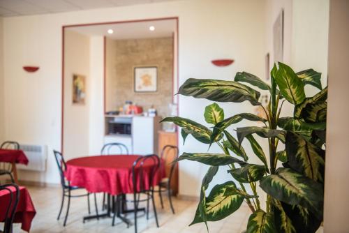 una sala da pranzo con tavolo rosso e pianta di Hotel Du Lez a Bollène