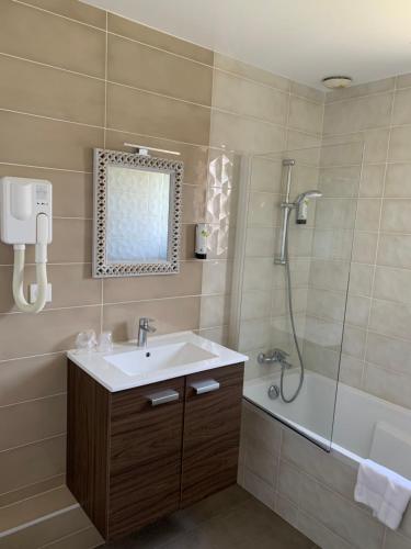 a bathroom with a shower, sink, and mirror at LOGIS-Auberge Les Vallees Du Perche in Vichères