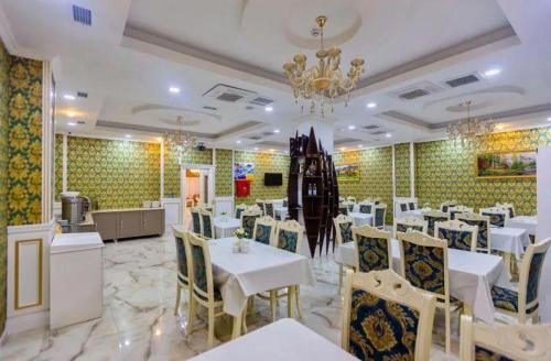 Mensen Hotel Baku في باكو: مطعم بطاولات بيضاء وكراسي وثريا