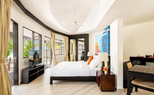 a bedroom with a white bed and a tv at Angsana Velavaru in Dhaalu Atoll