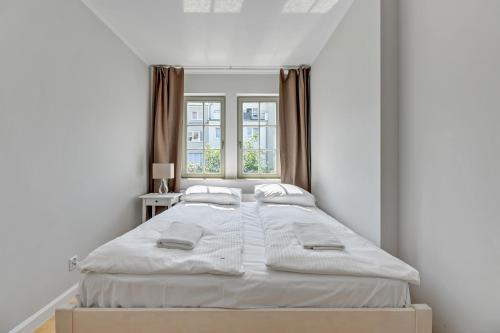 a white bedroom with two beds and a window at Grand Apartments - Lemon - Monte Cassino in Sopot