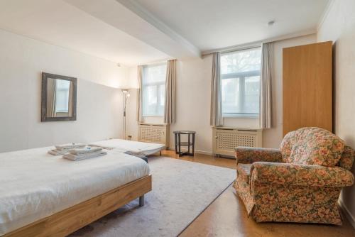 een slaapkamer met een bed, een stoel en ramen bij TOP& ruim duplex woning in PATERSHOL,centrum Gent! in Gent