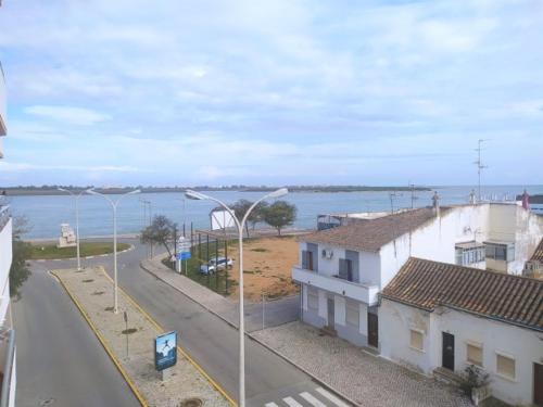 a view of a street with buildings and the water at Foz do Guadiana in Vila Real de Santo António