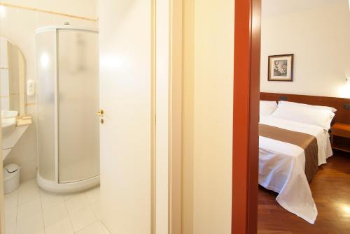 a bedroom with a bed and a walk in shower at Alla Rocca Hotel Conference & Restaurant in Bazzano