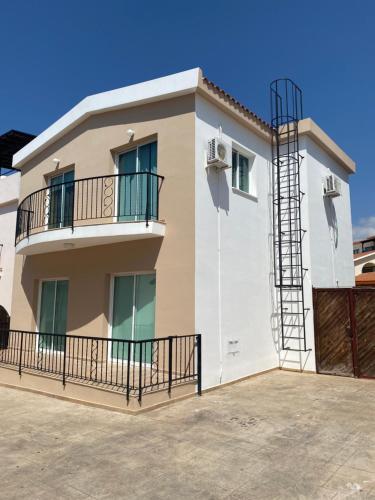 uma casa com uma varanda e um céu azul em Three Bedroom Casa de Paphos em Pafos