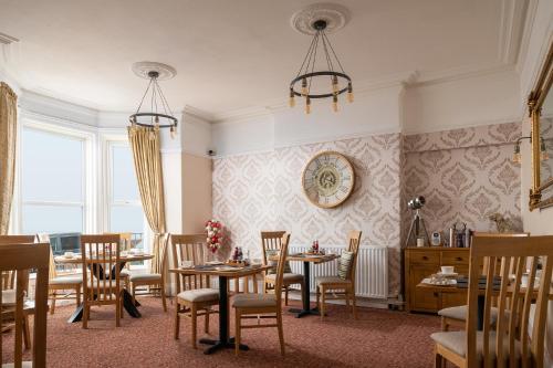 a dining room with tables and chairs and a clock on the wall at The Kendrick Exclusively for adults in Llandudno