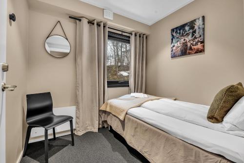 a bedroom with a bed and a chair and a window at Robukta Lodge in Tromsø