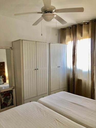 1 dormitorio con cama blanca y ventilador de techo en APARTAMENTO JALAMA 2D, en Moraleja