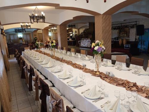 a long table in a room with white tables and chairs at Casa Boiereasca in Iaşi