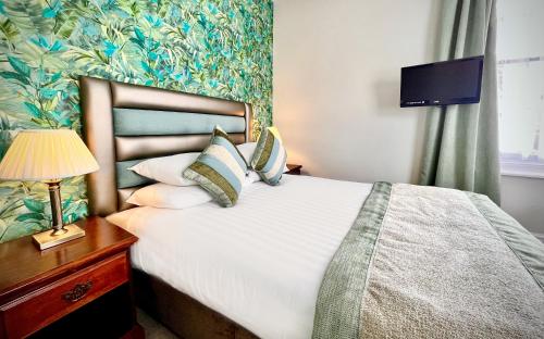 a bedroom with a bed and a tv on a wall at Abbey Sands Hotel in Torquay