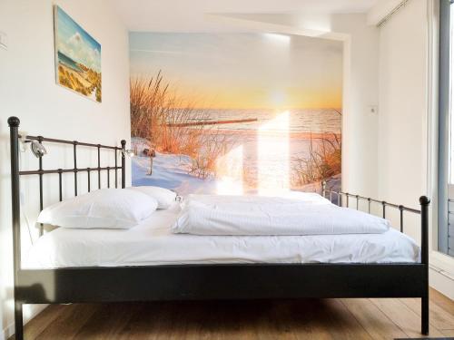 ein Bett in einem Schlafzimmer mit einem Gemälde eines Strandes in der Unterkunft Vakantiewoning Goedgelegen MB01 in Middelburg