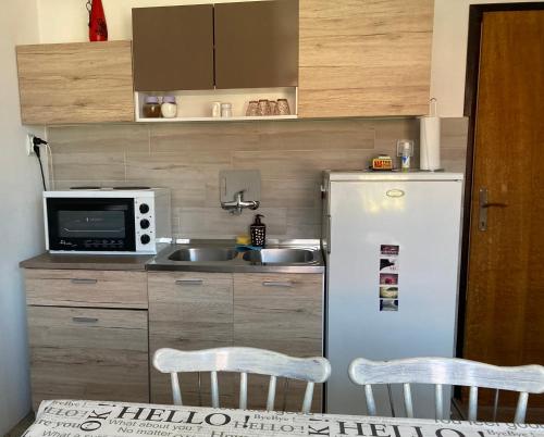 a small kitchen with a refrigerator and two chairs at Stan na dan Loznica in Loznica