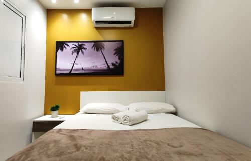 a bedroom with a bed with a picture on the wall at Areias do Mar ! 3 quartos com Varanda A212 in Barra de São Miguel