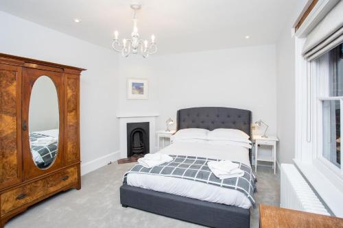een slaapkamer met een bed, een spiegel en een dressoir bij Torrington Hall in Saint Albans