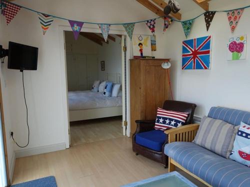 Una sala de estar con un sofá y un dormitorio. en Dunedin - Waterside location, private garden and buckets of charm, en Dittisham