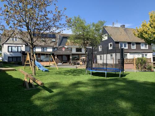 einen Hof mit Spielplatz vor einem Haus in der Unterkunft Pension Wittgensteiner Schweiz in Bad Berleburg