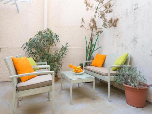 patio z 2 krzesłami i stołem z pomarańczowymi poduszkami w obiekcie Green Magic Apartment w Dubrowniku