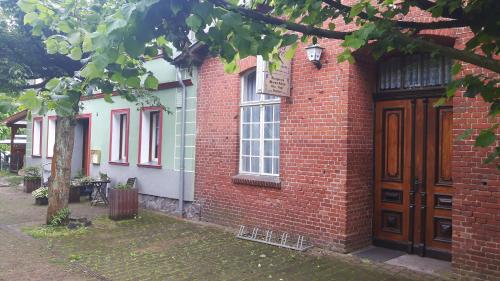 un edificio de ladrillo rojo con una puerta y un árbol en Gasthof Alte Fischerhütte, en Altfriesack