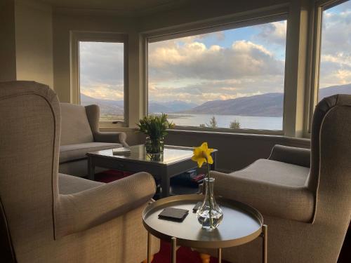 a living room with chairs and a table and a large window at Ardvreck House in Ullapool