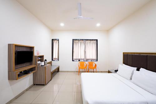a hotel room with a bed and a television at Agrasen Foundation Managed by TGB foods Pvt Ltd in Ahmedabad