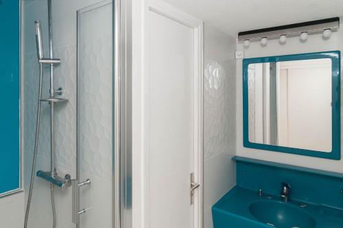 une salle de bain avec un lavabo bleu et un miroir dans l'établissement Appartement Village Naturiste Hermès, au Cap d'Agde