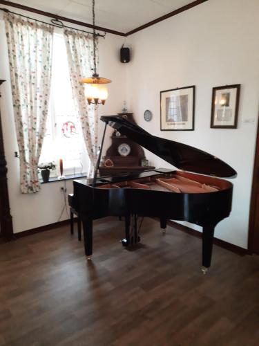 a black piano in a room with a window at Hotel zur Brücke in Kevelaer