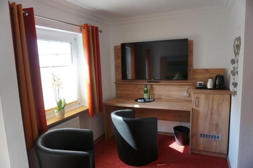 a room with a desk with a television and two chairs at Hotel Jan van Werth in Koblenz