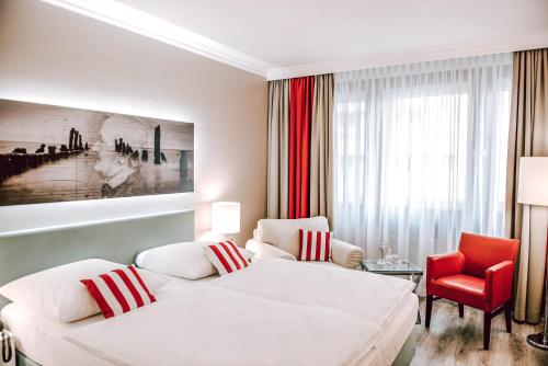 Concorde Business Boutique Hotel في باد سودن آم تاونوس: غرفة فندق بها سريران وكرسي أحمر