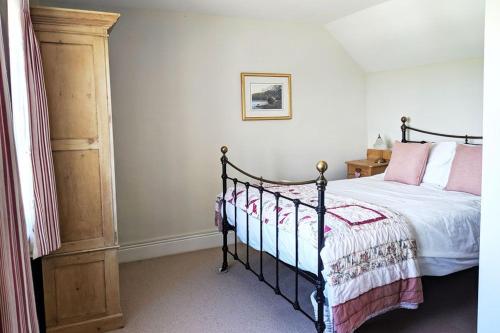 a bedroom with a bed with pink and white sheets at 1 Rock Cottage - Beautifully Presented Cottage for Four with Wood Burner in Dittisham