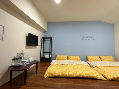 a bedroom with two beds and a table and a wall at Xingang Ping An B&B in Xingang