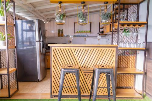 a kitchen with a bar with two stools and a refrigerator at Hotel Plataneras Plaza in Apartadó