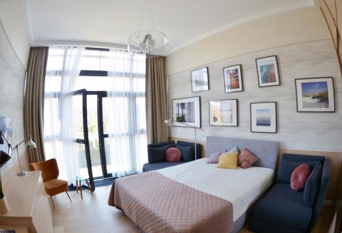 een slaapkamer met een bed en twee blauwe stoelen bij Apartament 102 - Mielno Dune A - Pool & Beach in Mielno