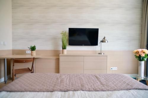 een slaapkamer met een bed en een bureau met een televisie bij Apartament 102 - Mielno Dune A - Pool & Beach in Mielno