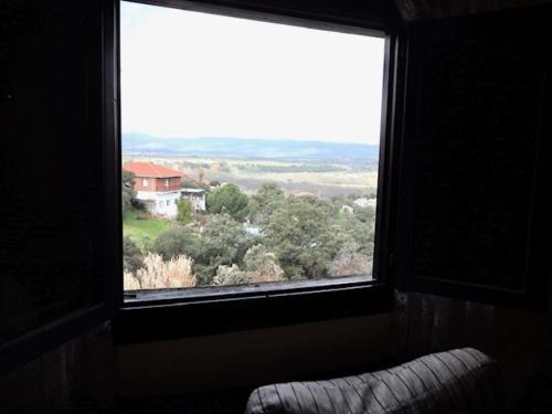 a window with a view of a house and trees at Paradise in Aldea del Fresno