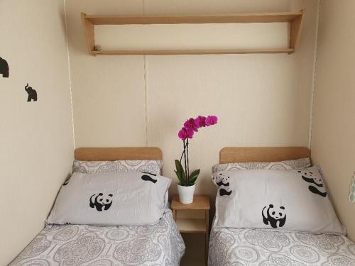 2 Betten in einem Zimmer mit Panda-Kissen und einer Vase mit Blumen in der Unterkunft Beaches45 in Hythe